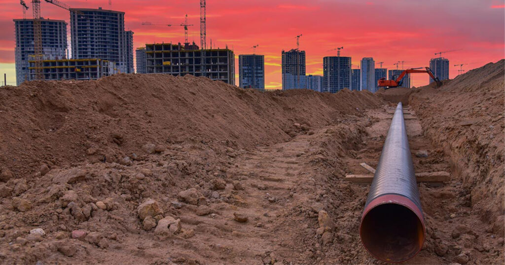 Travaux d'infrastructure liés à la gestion de l'eau, mettant en avant un chantier de canalisation sous un ciel au coucher de soleil, symbolisant les défis de la gestion des eaux pluviales en milieu urbain.